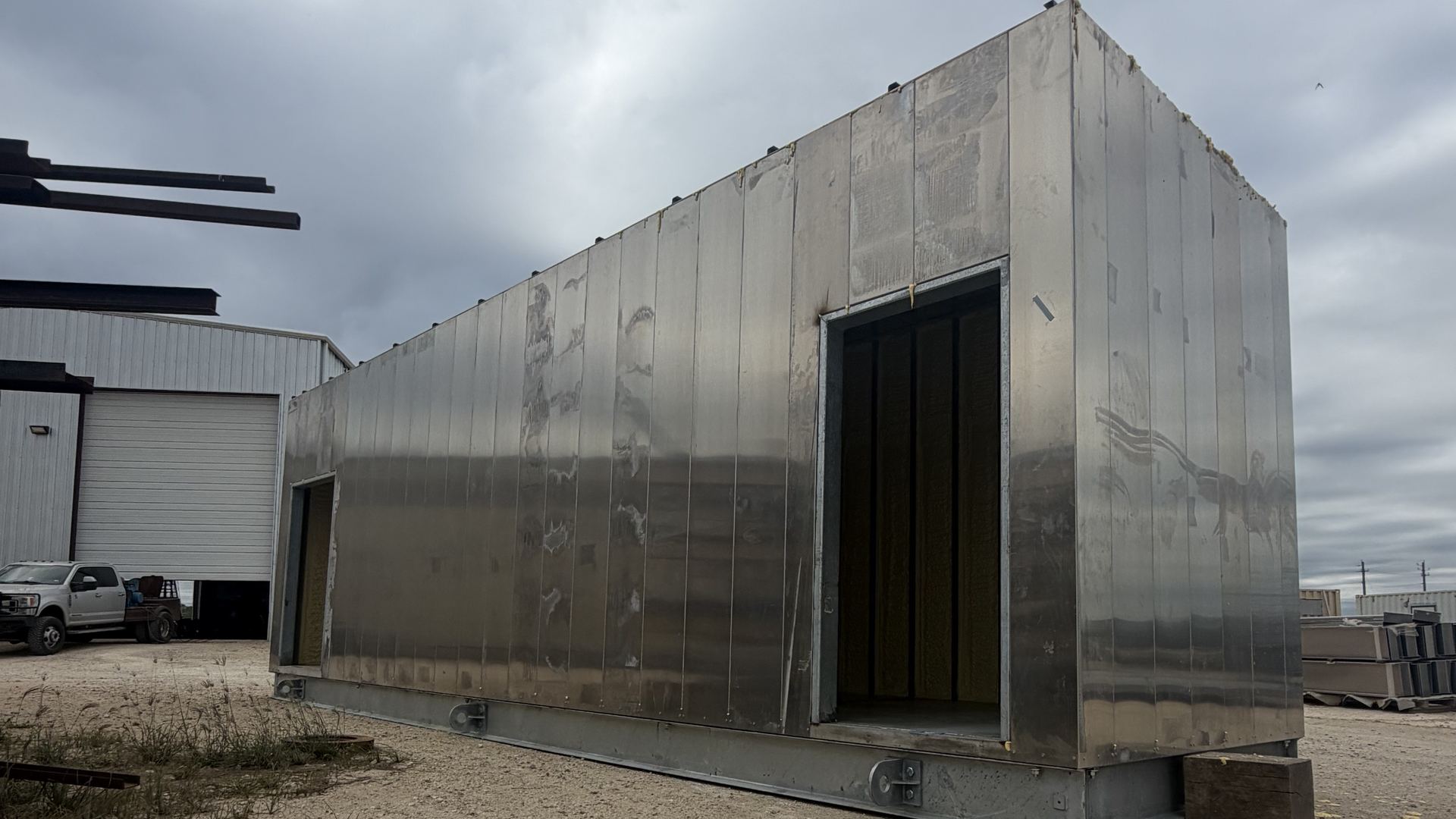 Finished aluminum-clad enclosure on a steel base outside the shop