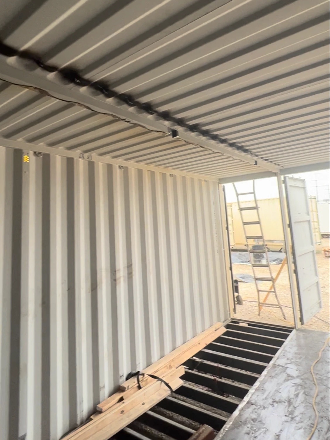 Welded roof seam and open floor framing inside a container under fabrication